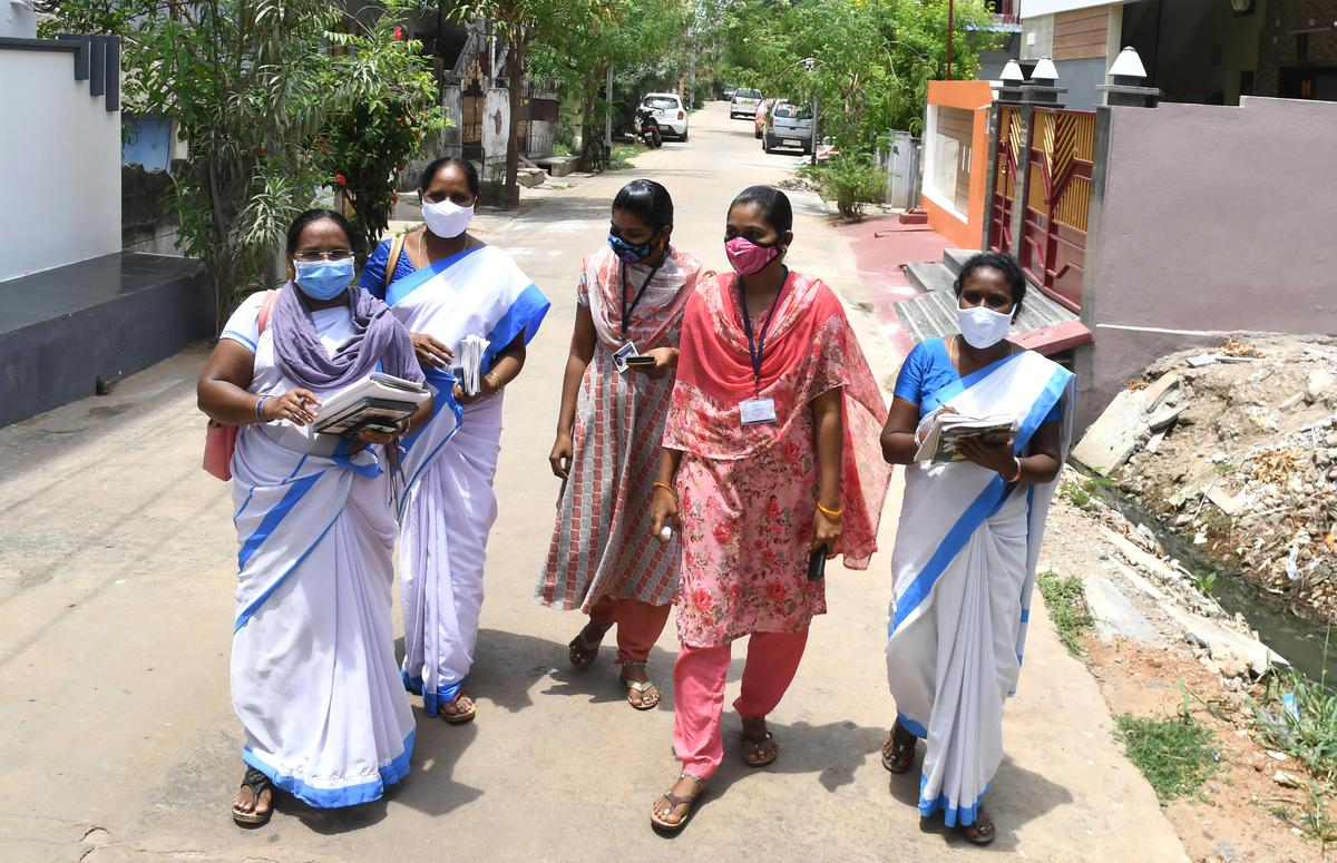 5 ASHA workers walking on a street, face masks on and papers in hand