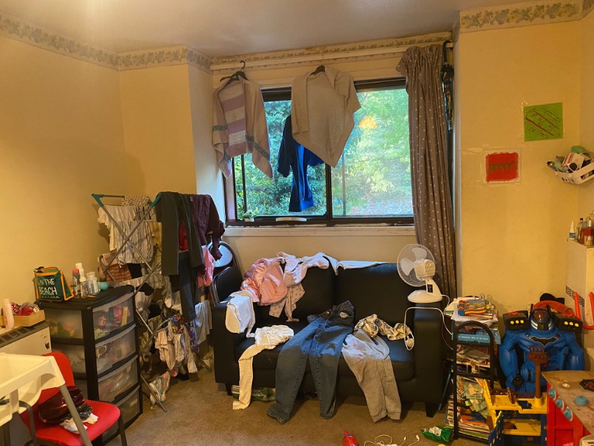 Picture of clothes laying out on a sofa to dry. More clothes hang above the sofa, and on a clothes horse beside it