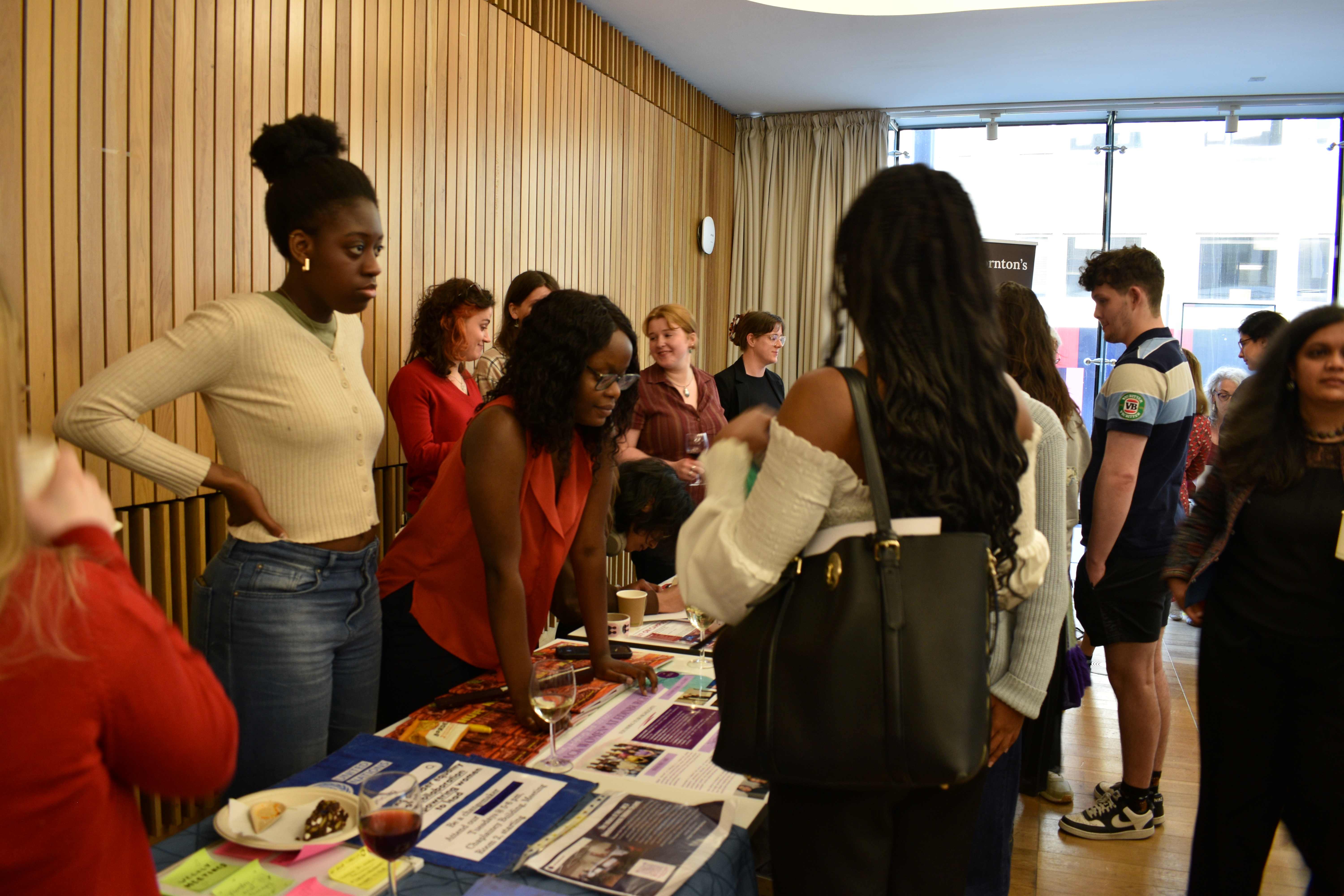 Members of Black Women* at Edinburgh, Claudia Efemini and Rutendo Amanda Hoto at the Black Women* at Edinburgh stand at the Annual Research Showcase. They are chatting to people at their stand.