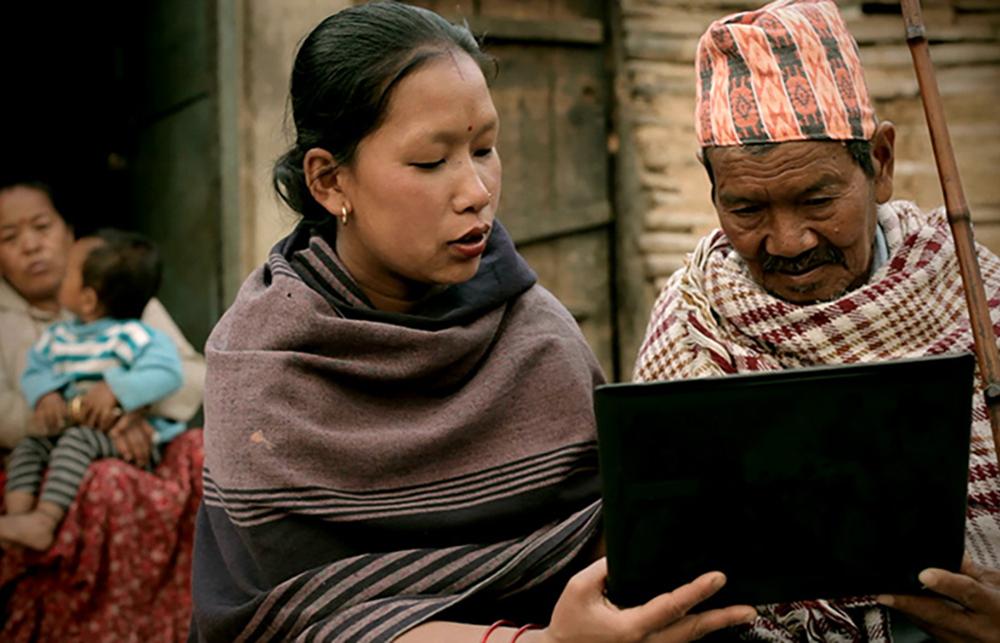 Two people look at a laptop