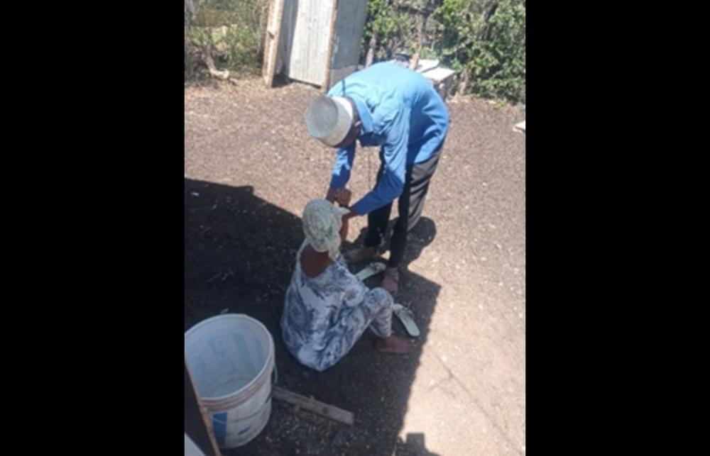 A male Community Health Volunteer in Isiolo, northern Kenya, bends down to assess a seated pregnant patient.