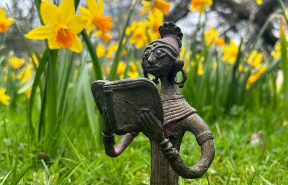 Statue reading in front of Daffodils 